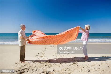 Senior Couple Spreading Blanket On Beach Photo Getty Images
