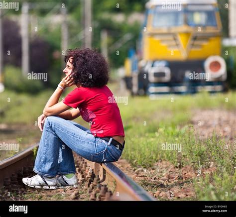 Young Redhead Woman Sitting On Rail Tracks In A Railroad With A