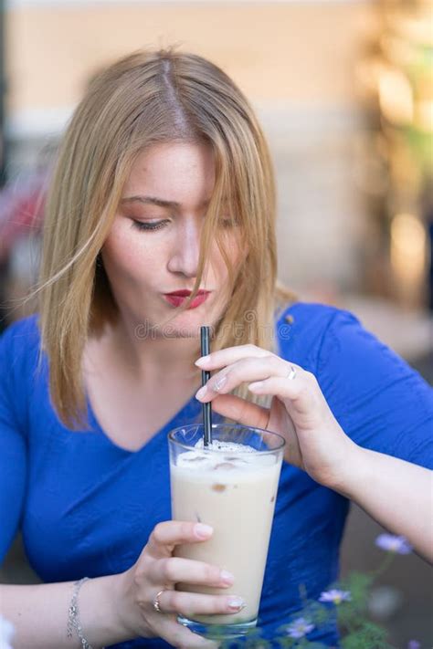 Charming Caucasian Blonde Girl In A Blue Dress Sitting At A Table In A