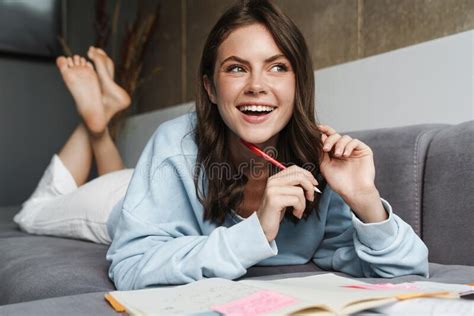 Image Of Woman Doing Homework With Exercise Books While Lying On Sofa