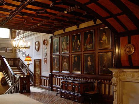 An Ornate Room With Many Portraits On The Wall And Wooden Staircase