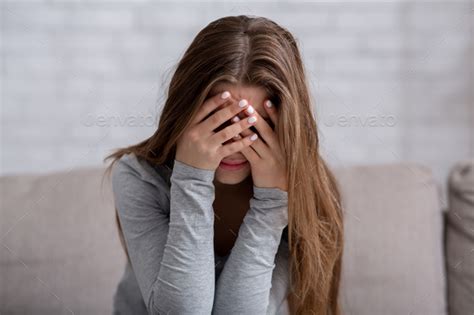 Millennial Woman Covering Her Face With Hands And Crying Feeling Depressed Or Stressed Stock