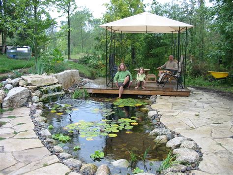 A pond pool by waterhouse pools and ponds at this upscale rustic residence features a sunken patio floor and a floating stone diving platform. Ponds And Waterfalls | ROBIN AGGUS - Natural Landscaping