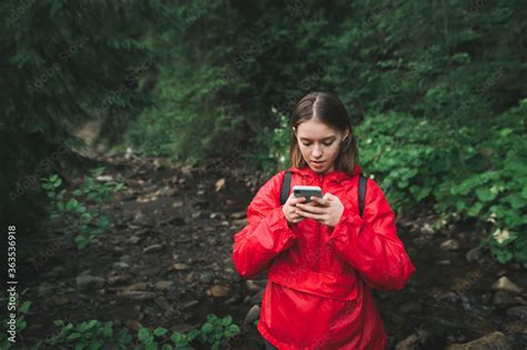 Young Female Hiker Is Concentrated On Her Smartphone Texting And Feeling Puzzled In The Fir