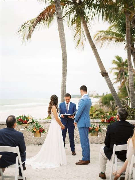 A Bride And Groom Are Getting Married Under Palm Trees