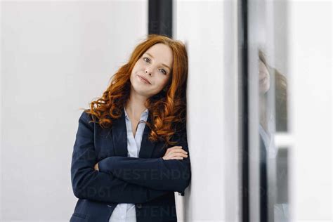 Portrait Of Redheaded Businesswoman Leaning Against A Wall Stock Photo