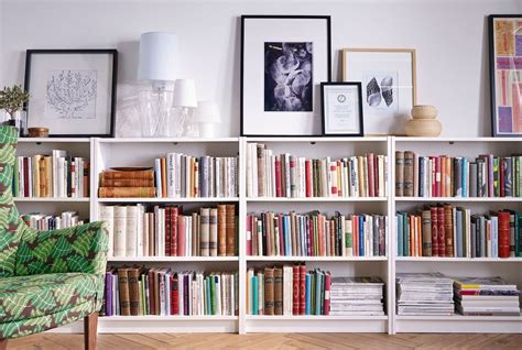 A Row Of Ikea Bookcases Lines A Wall On Top Is Framed Art And Lamps
