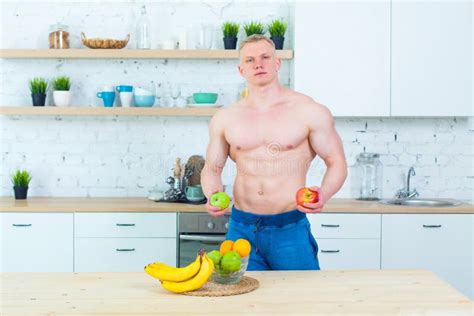 Muscular Man With A Naked Torso In The Kitchen With Fruit Concept Of