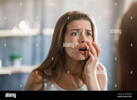 Shocked Woman Touching Acne On Her Cheek While Looking In Mirror At Home Stock Photo Alamy
