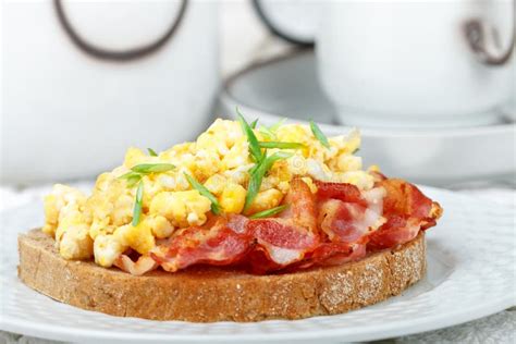 Bread Toast With Scrambled Eggs Fried Bacon And Green Onions Close Up