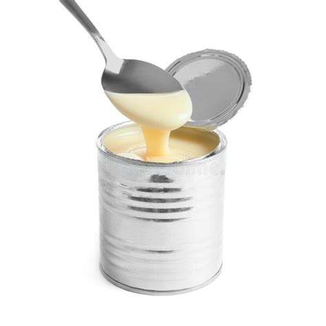 Condensed Milk Pouring From Spoon Into Tin Can On White Background