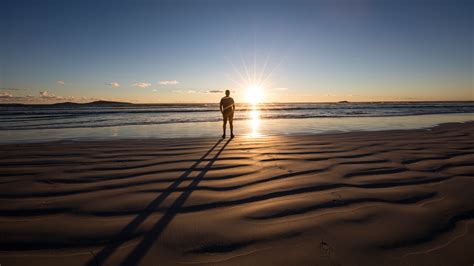 Man Standing On Beach Looking At The Sunset Western