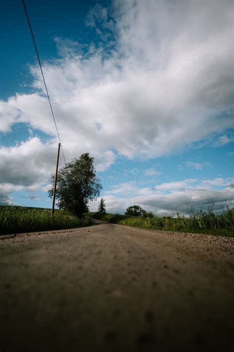 Vertical Shot Of A Countryside Gravel Road Under A Cloudy Sky Stock