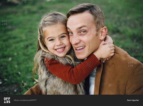 Young Girl With Her Arms Wrapped Around Her Dads Neck Hugging Tight