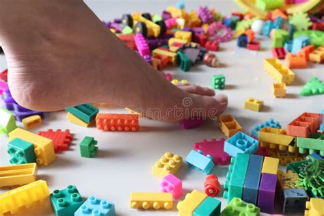 Close Up Side View Of Foot Stepping On Scattered Legos On The Floor