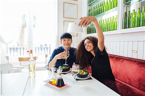 Multi Ethnic Couple Taking A Selfie Whilst Eating In A Cool Restaurant By Stocksy Contributor