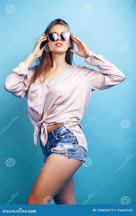 Young Pretty Girl In Sunglasses Posing Happy Smiling On Blue Background