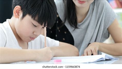 Serious Asian Mother Son Doing Homework Stock Photo