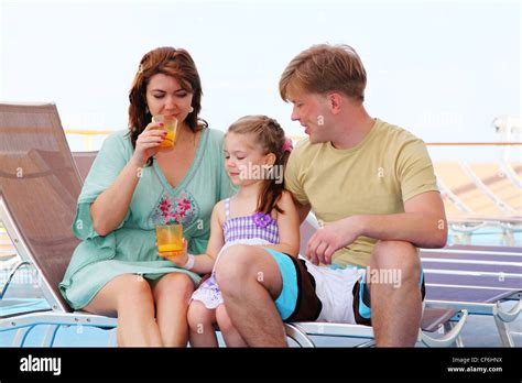 Mom Dad And Daughter Rest On Deck Of Yacht And Drink Tasty Juice Stock
