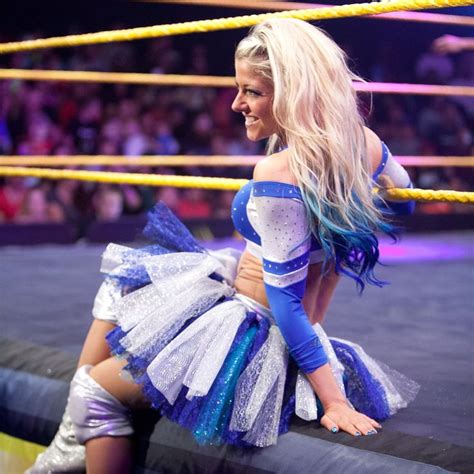 A Woman In Blue And White Outfit Sitting On Top Of A Wrestling Ring