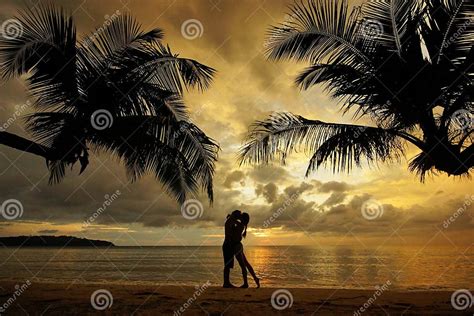 Silhouette Of Kissing Couple Standing On Tropical Beach During Sunset