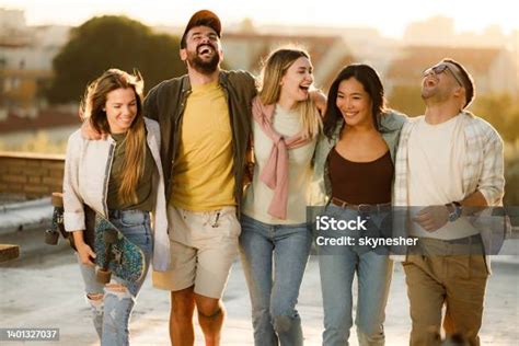 Amigos Felices Caminando Abrazados En Un Techo Al Atardecer Foto De