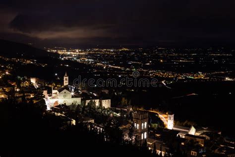 aerial view of assisi town umbria italy and valley at night with city lights and santa chiara