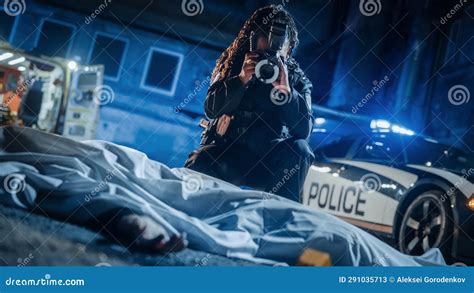 Black Female Police Officer Using Camera With Flash To Take Photos Of A Dead Body Covered By A