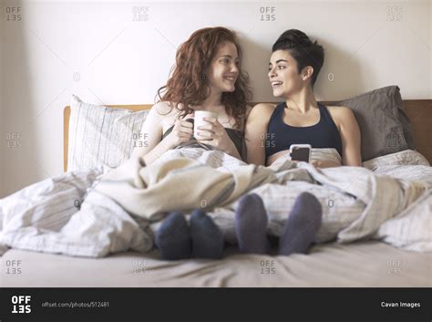 Happy Lesbian Couple Looking At Each Other While Sitting On Bed Stock