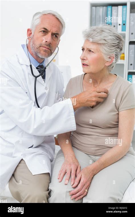 Male Doctor Checking Senior Patients Heartbeat Using Stethoscope Stock