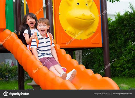 Two Kids Friends Having Fun To Play Together On Childrens Slide Stock