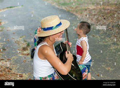 El niño y su mamá están jugando fuera Mamá entretiene a su hijo mientras toca la guitarra La