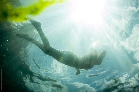 Slender Woman Swimming In A Clear River Del Colaborador De Stocksy