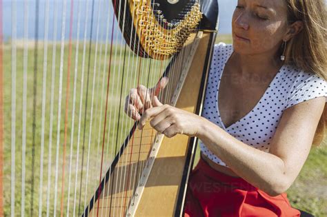 Young Woman Playing Harp During Sunny Day Stock Photo