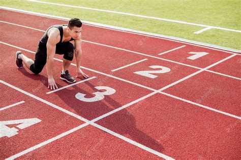 Premium Photo Young Male Runner Taking Ready To Start Position On Race Track