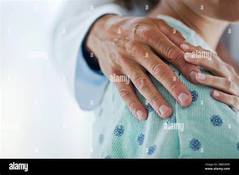 Hospital patient touches the comforting hand laid on her shoulder Stock