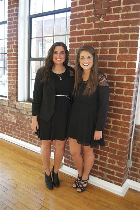 Two Women Standing Next To Each Other In Front Of A Brick Wall With