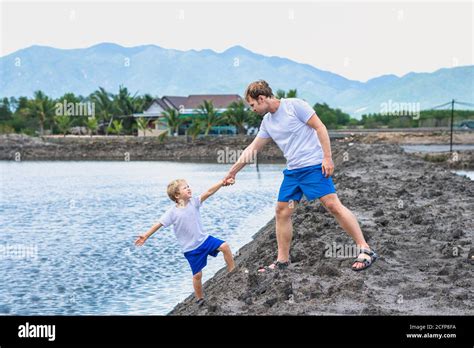 Dad helps son go down to lake water, explains safety rules. Family