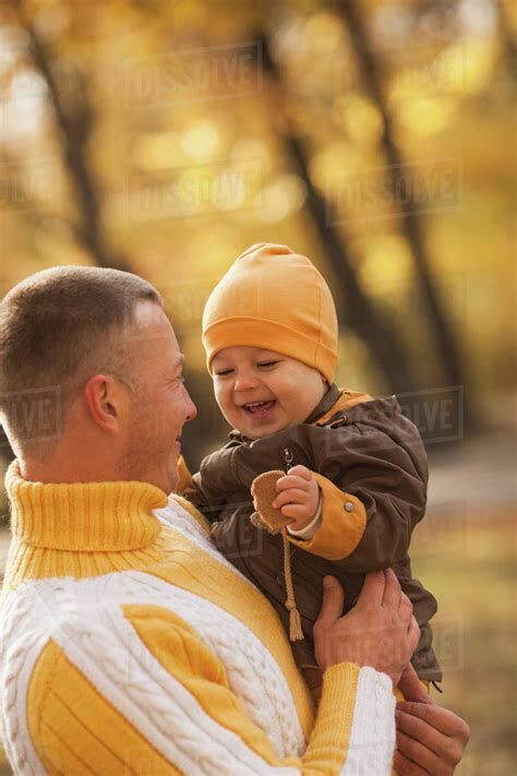Cheerful Baby Boy Being Carried By Father At Park During Autumn Stock