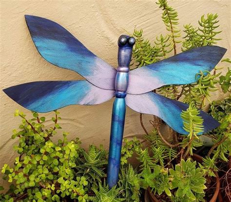 A Blue And Purple Dragonfly Sitting On Top Of A Plant