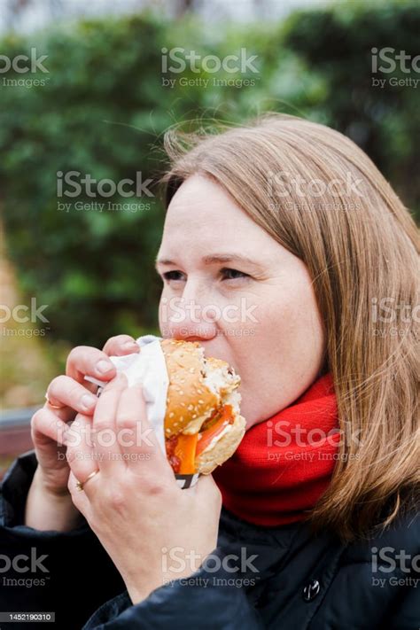 소녀 큰 햄버거 치즈 버거를 먹는 여자 정크 지방 맛있는 길거리 음식 햄버거를 가져 가라 벤치에 앉아 공원에서 야외에서 점심