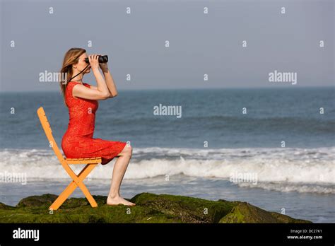 reife frau mit dem fernglas auf stuhl am strand sitzend stockfotografie alamy