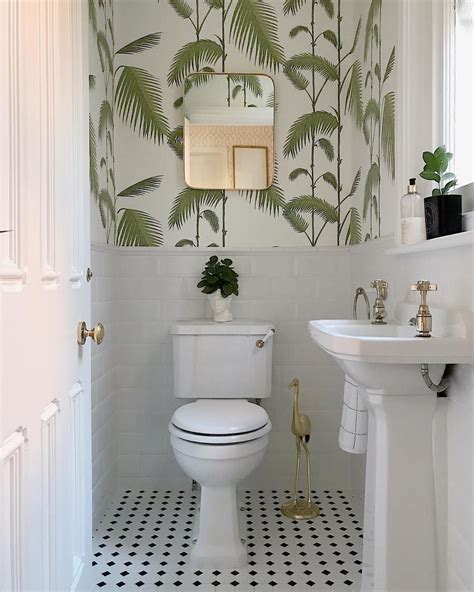 A Beautiful White Bathroom With Gold Accessories And Botanical