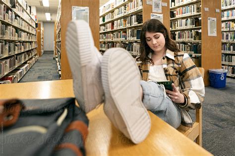 Girl Student With Feet On Library Table Del Colaborador De Stocksy