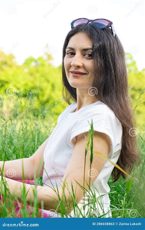portrait of a 35 year old brunette woman looking at the camera smiling in nature stock image