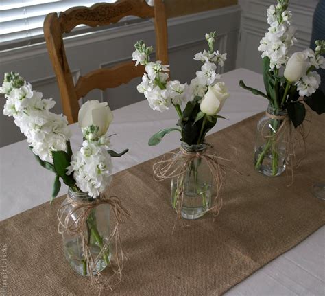 Three Vases With White Flowers Are Sitting On A Dining Room Table