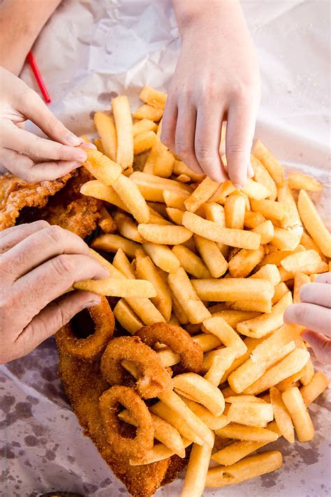 Many Hands Reaching For Chips Takeaway Fish And Chips On A Picnic Table By The Sea By Stocksy