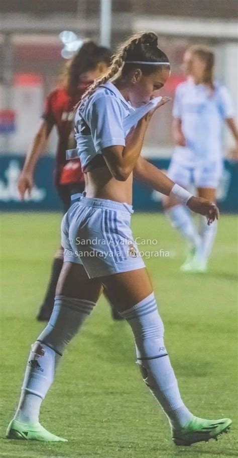 A Female Soccer Player Is On The Field With Her Foot In The Air And Looking Down