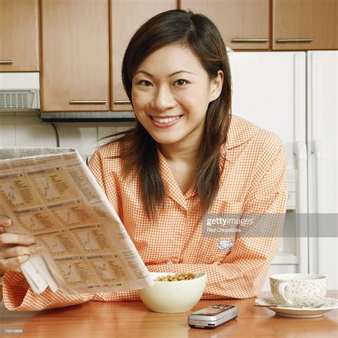 Portrait Of A Young Woman Holding A Newspaper At A Kitchen Counter