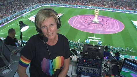 ZDF-Moderatorin sitzt mit Regenbogen-Binde und -Shirt im Stadion - Fans